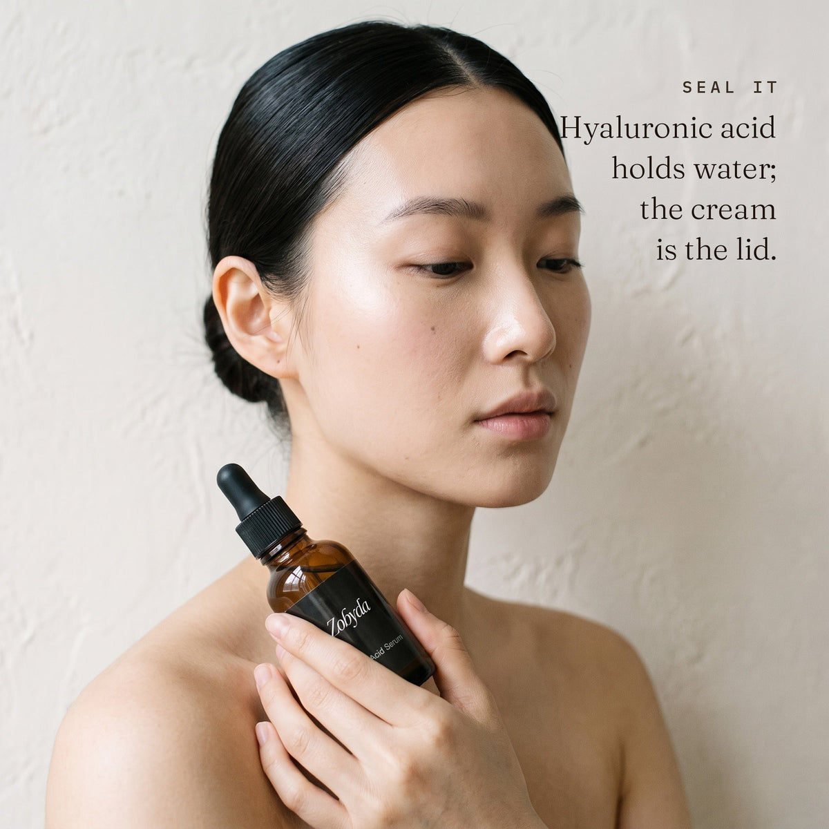 Woman holding the Zobyda Hyaluronic Acid Serum bottle, sealed in with night creme over the top